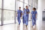 Four healthcare workers in scrubs walking in corridor